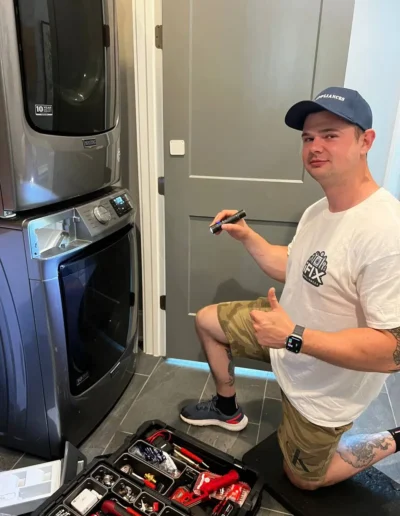 iFix Appliance technician servicing a stacked washer and dryer with a tool kit in Raleigh, NC.